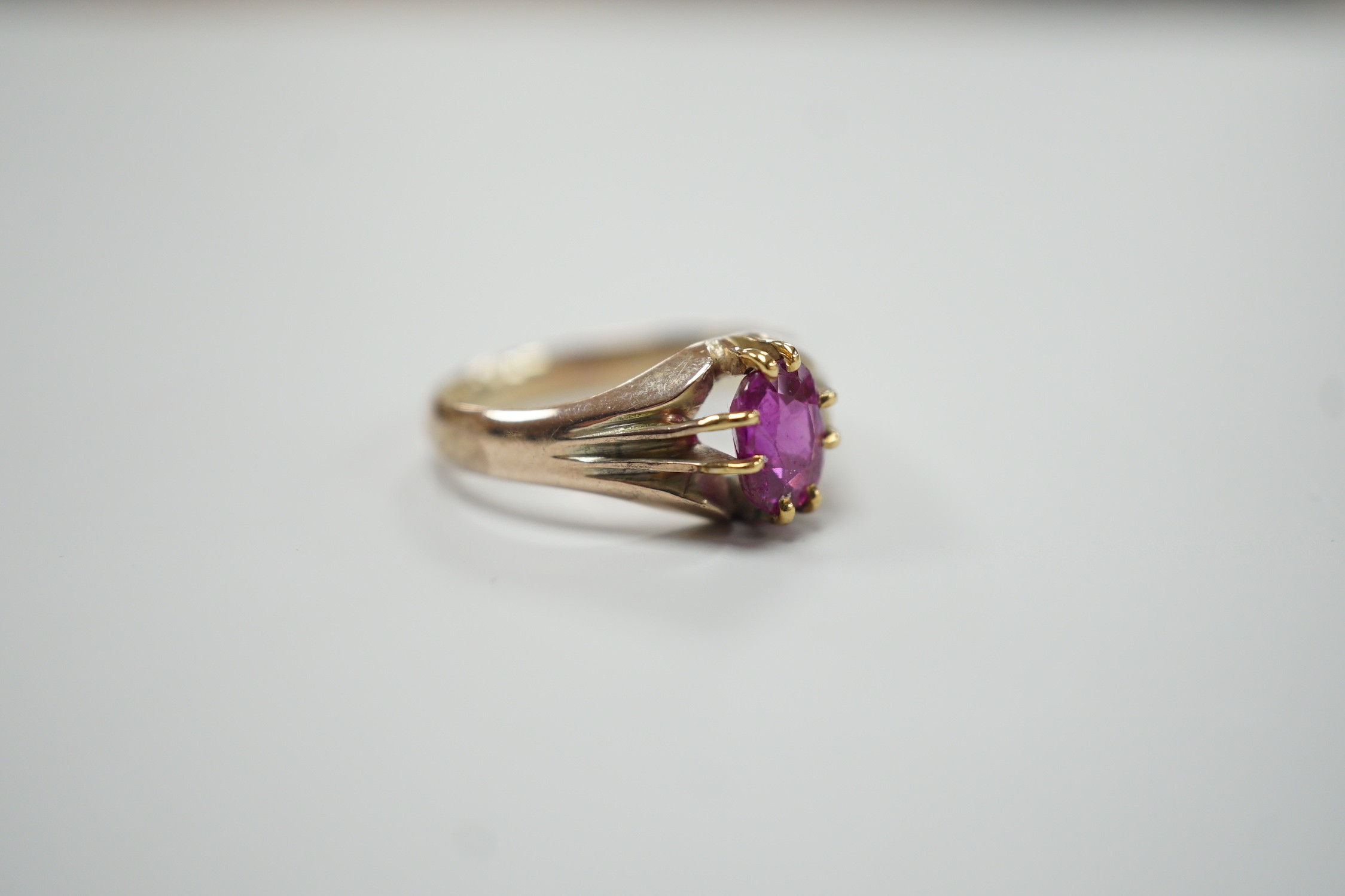 A yellow metal and claw set solitaire oval cut ruby/pink sapphire? ring, size L, gross weight 3.3 grams